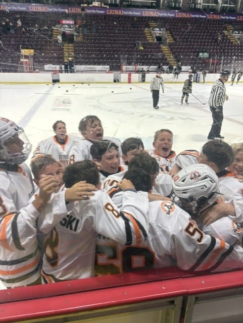 Compuware players huddle together at the bench in celebration