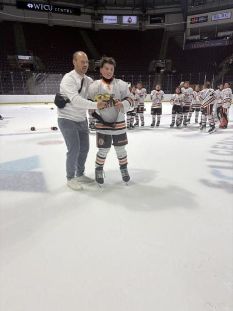 A coach presents a Compuware player with the tournament's signature MVP belt